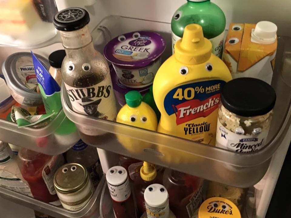 a refrigerator full of food with googley eyes on it