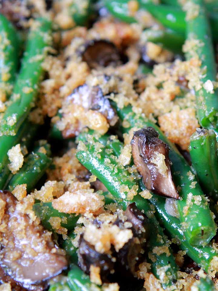 A close up on green beans in mushroom cream sauce with crushed pork rinds on top