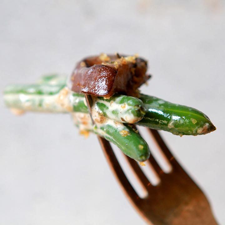 a fork holds 2 green beans and a mushroom