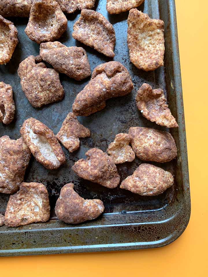 a gray cookie sheet covered with sweet cinnamon keto pork rinds