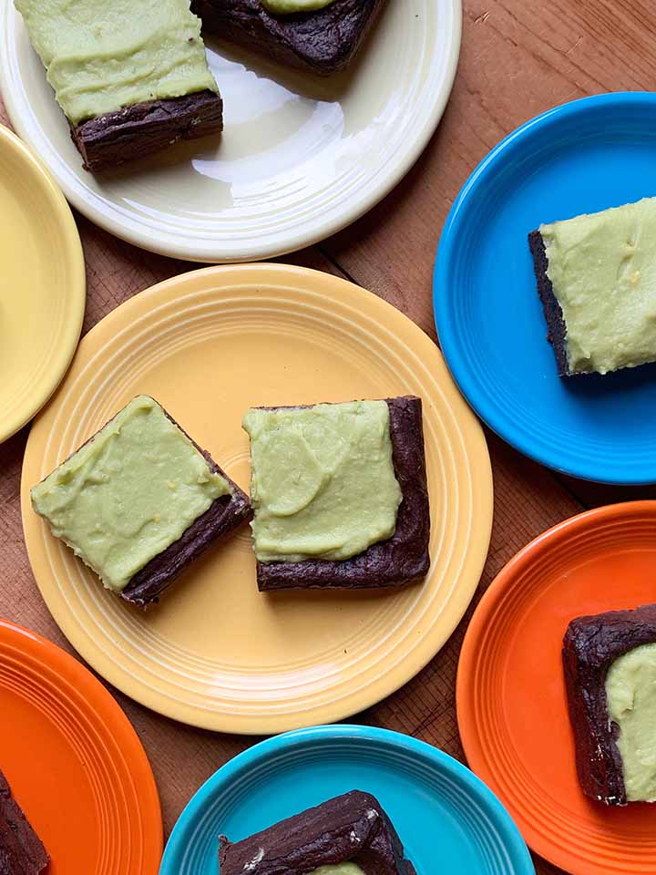 Multiple colored plates hold slices of easy avocado brownies