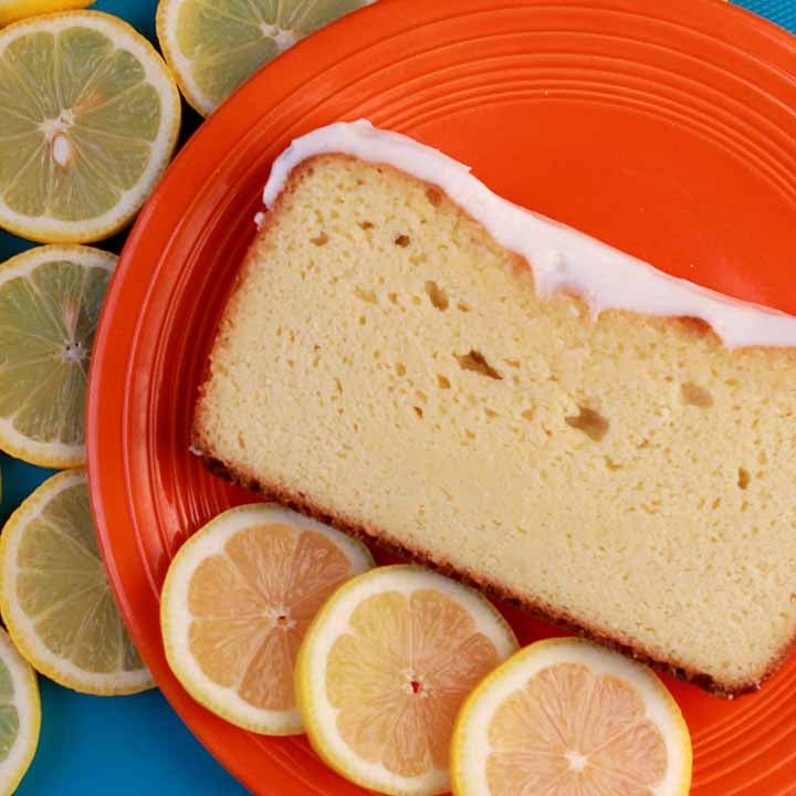 a top down shot of a slice of Keto Lemon Pound Cake on an orange plate, surrounded by lemon slices