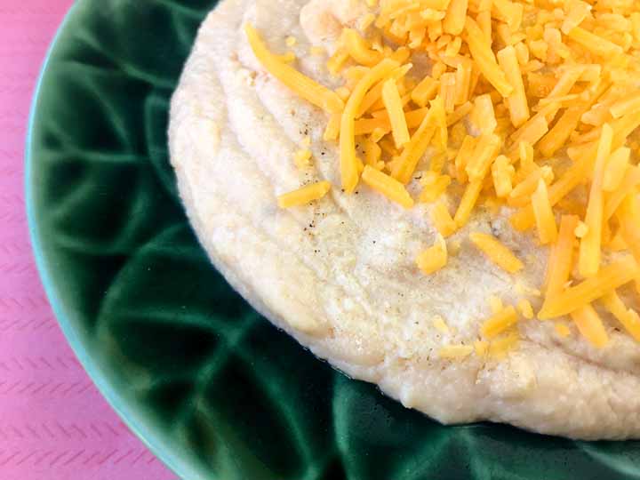 A close up shot of a green plate of gluten free cheese grits