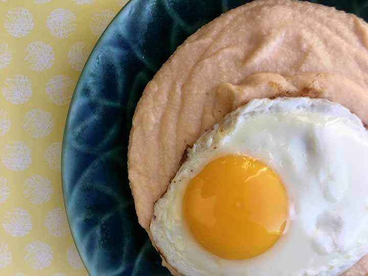 A green plate holds a a serving of grain free cheese grits with an egg on top
