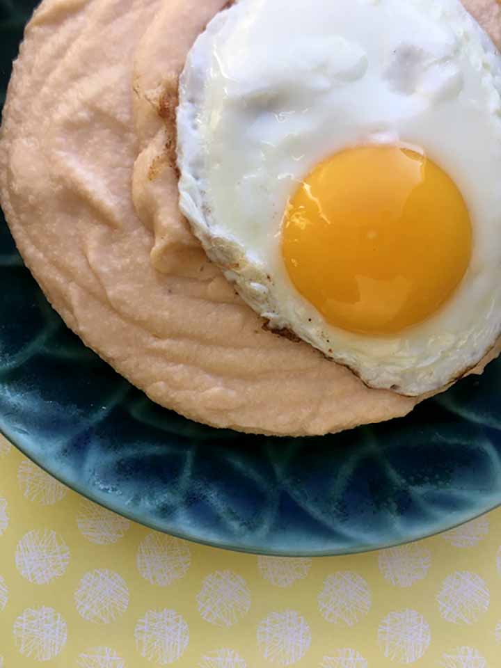 A green plate holds a a serving of Paleo cheese grits with an egg on top