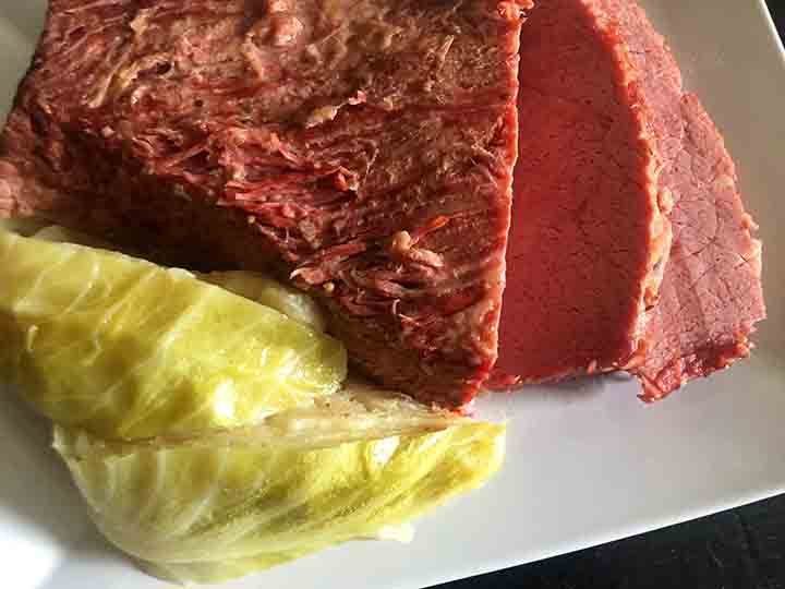 A white platter holds a low carb corned beef with Keto friendly cabbage