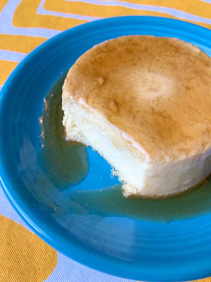 a piece of Keto flan with a bite taken out of it on a blue plate