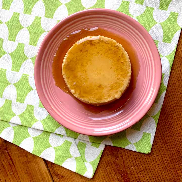 a piece of grain free flan on a pink plate against a white and green patterned background