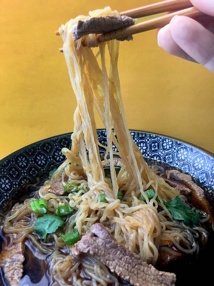 a hand holding shirataki noodles with chopsticks