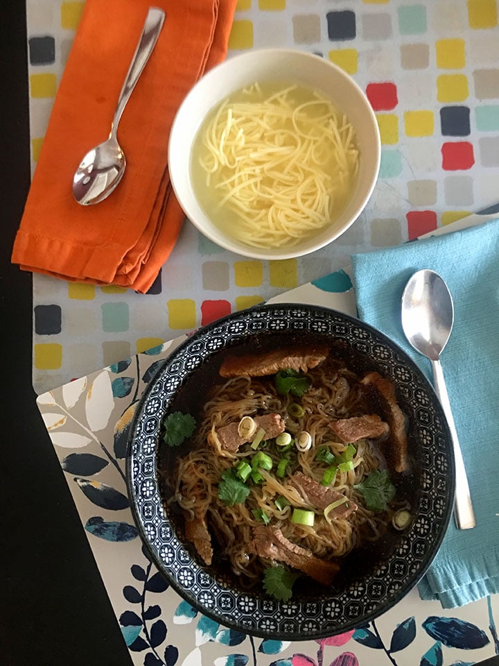 Two place settings: one classic noodle soup for a kid and one classic Vietnamese soup for an adult