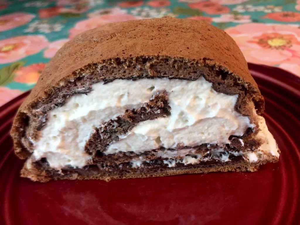 A slice of gluten free chocolate swiss roll on a plate