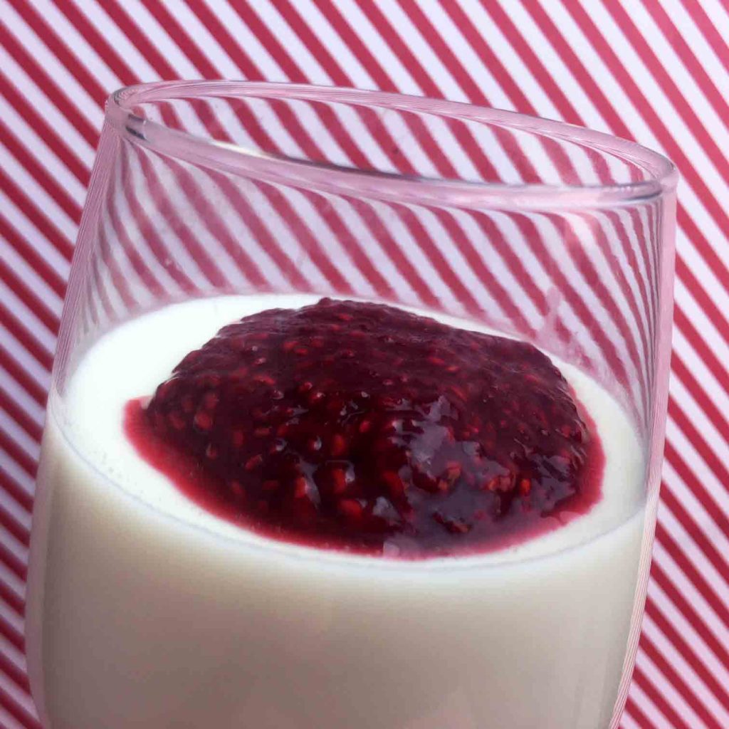 a glass holding Keto Panna Cotta with Raspberry Sauce