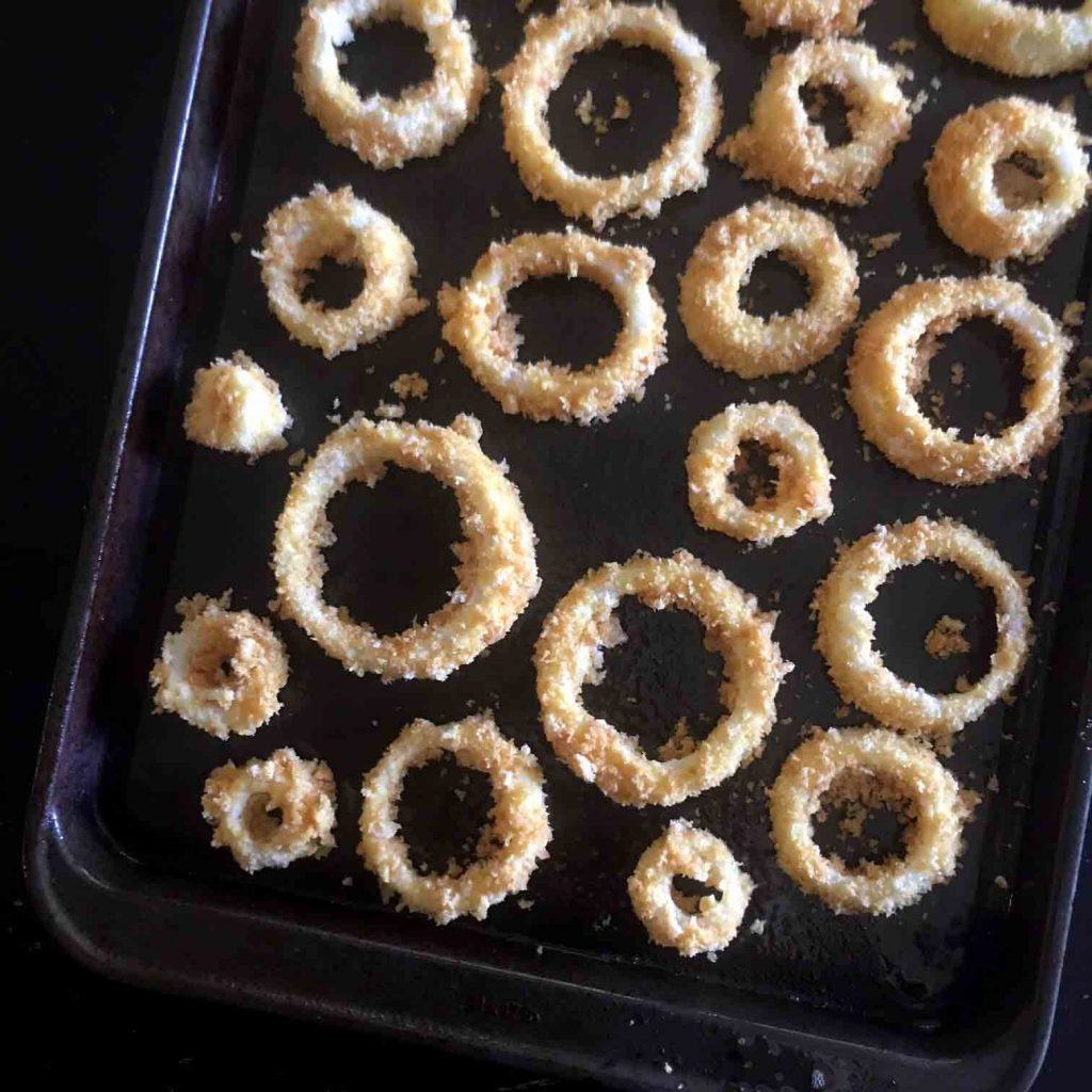 a top down view of a sheet pan full of pork rind crusted onion rings