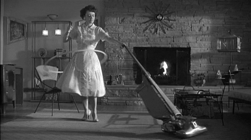 A gif of a vintage 1950's housewife who is hula hooping while vacuuming