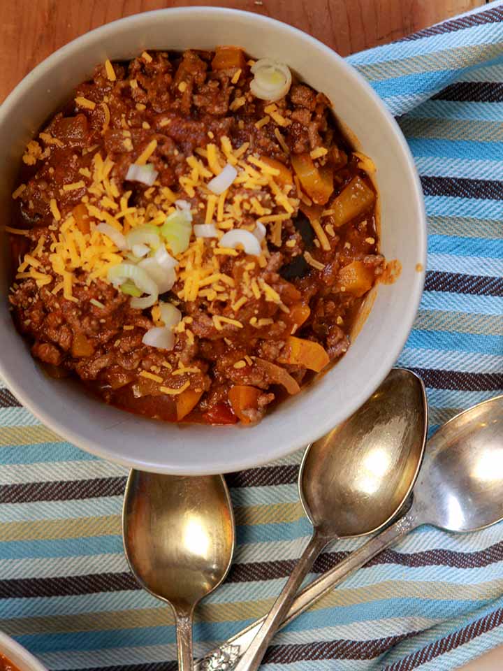 a top down view of a bowl of Keto chili con carne and several spoons