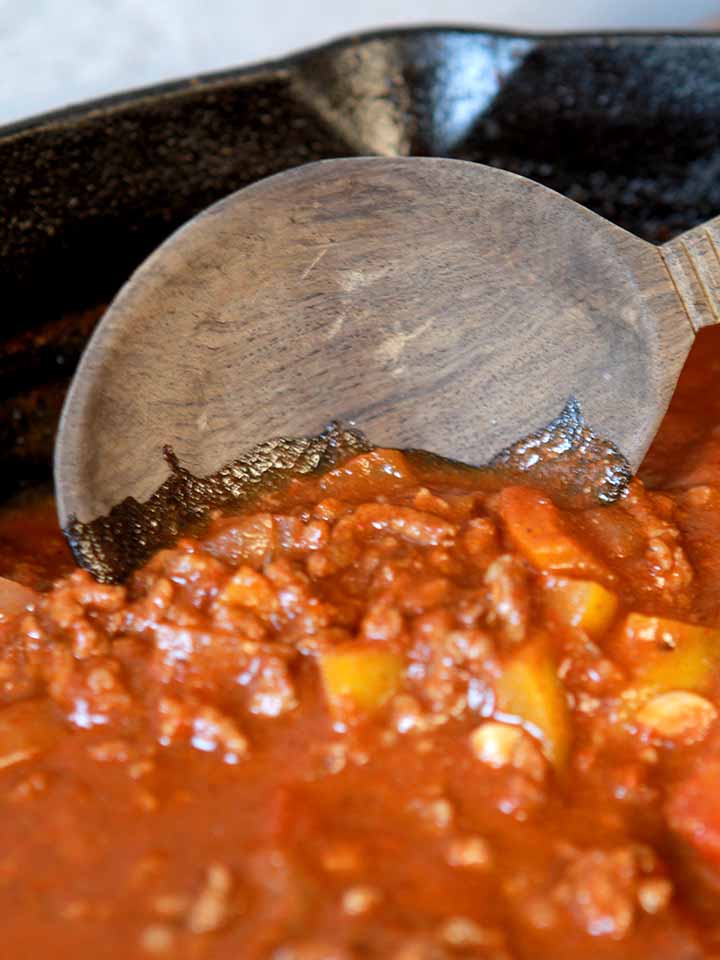 a wooden spoon scoops up some chili con carne
