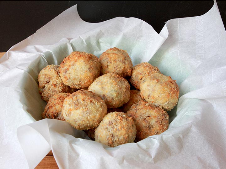 A basket filled with gluten-free sausage balls against a black background