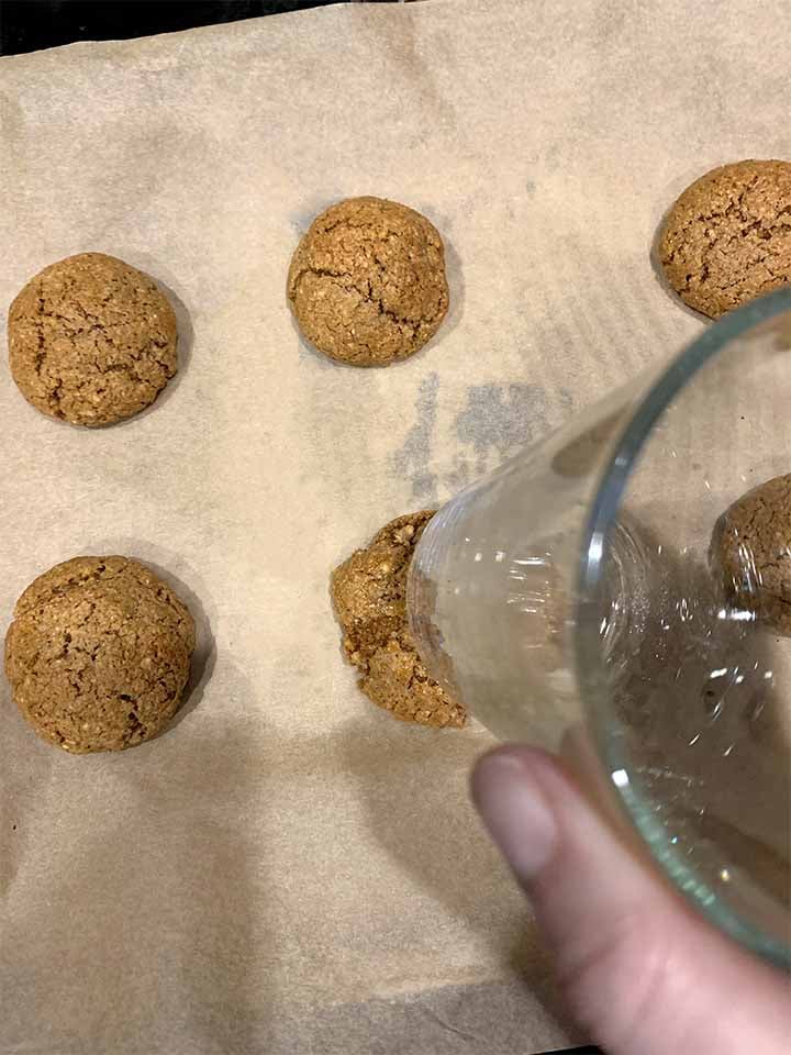 a hand presses down on the cookies with a glass