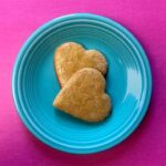 2 Keto gingerbread cookies on a blue plate against a bright pink background