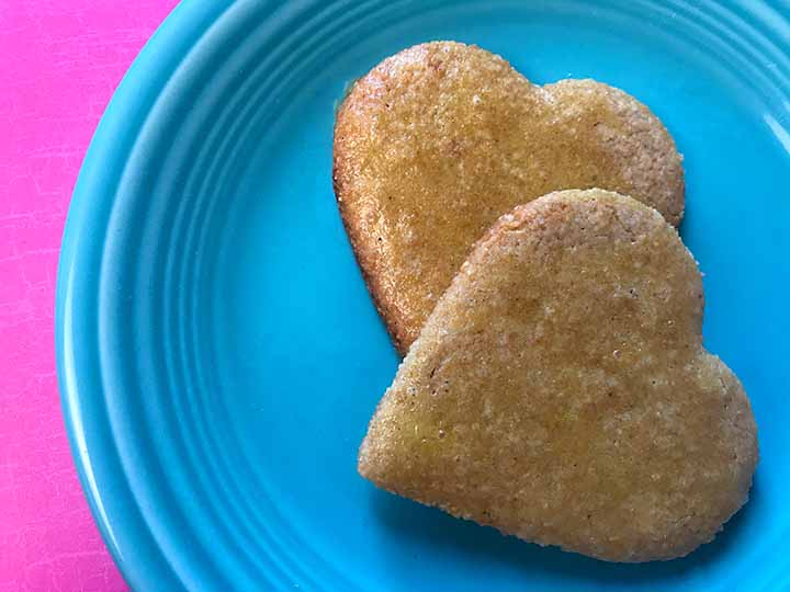 2 sugar free gingerbread cookies on a blue plate against a right pink background