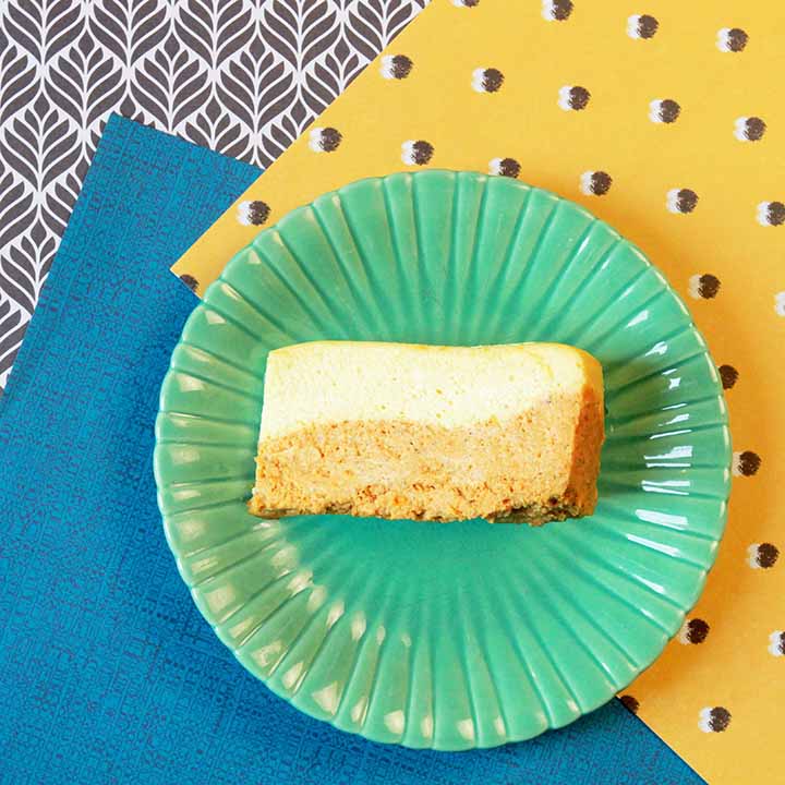 a slice of NY style layered pumpkin cheesecake against crazy patterned backgrounds