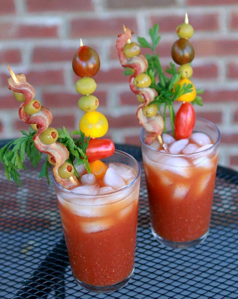 two glasses of Paleo Bloody Marys on a metal tabletop against a brick wall