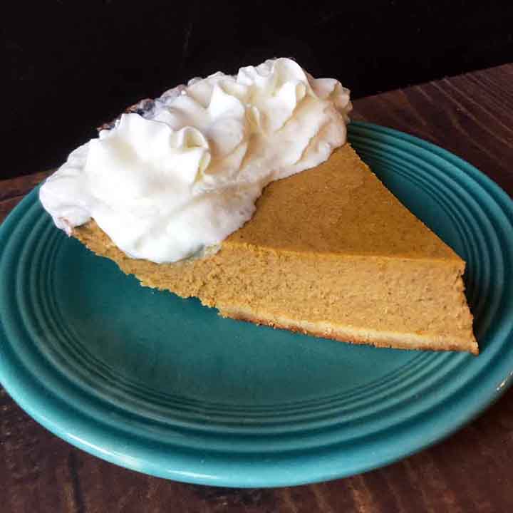 A side view of a slice of gluten free pumpkin pie on a blue plate