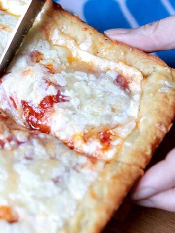 a hand picks up a slice of Keto Deep Dish Pizza