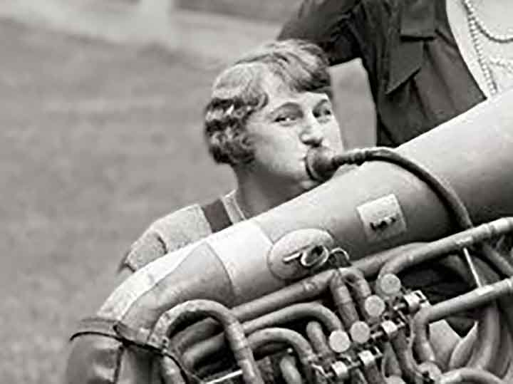 a 1920's photo of a woman playing a huge horn