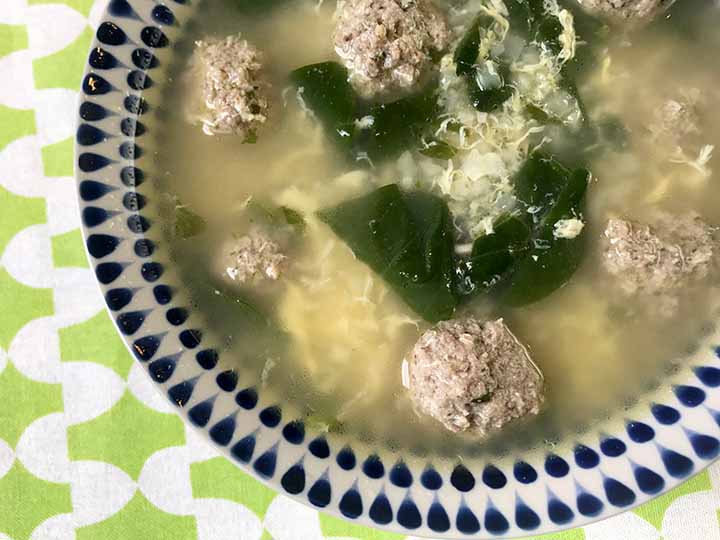 a bowl of Paleo meatball soup against a green and white patterned background