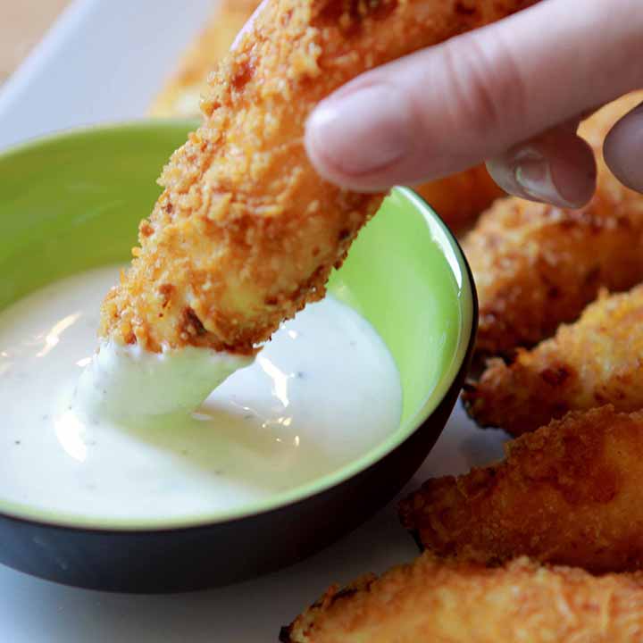 a hand dips a low carb chicken nugget