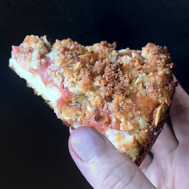 A hand holds s slice of Low Carb Keto Rhubarb Coffee Cake