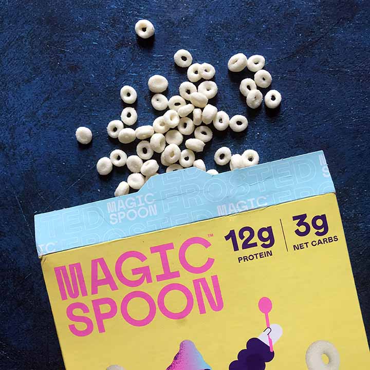 a open box of Magic Spoon Low Crab Cereal with cereal spilling out against a blue background
