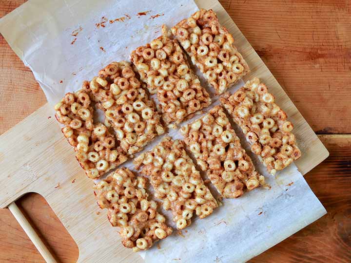 a top down view of 8 low carb keto cereal bars on white parchment paper against a wooden tabletop