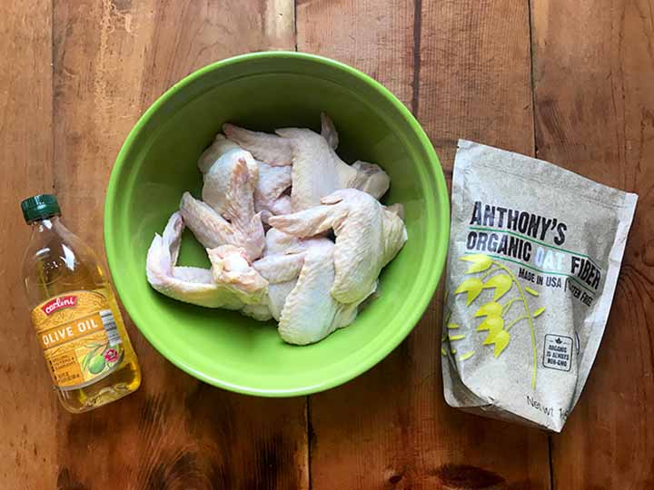 A bowl of chicken wings, a bag of oat fiber and a bottom of olive oil are the ingredients for Korean BBQ Chicken Wings