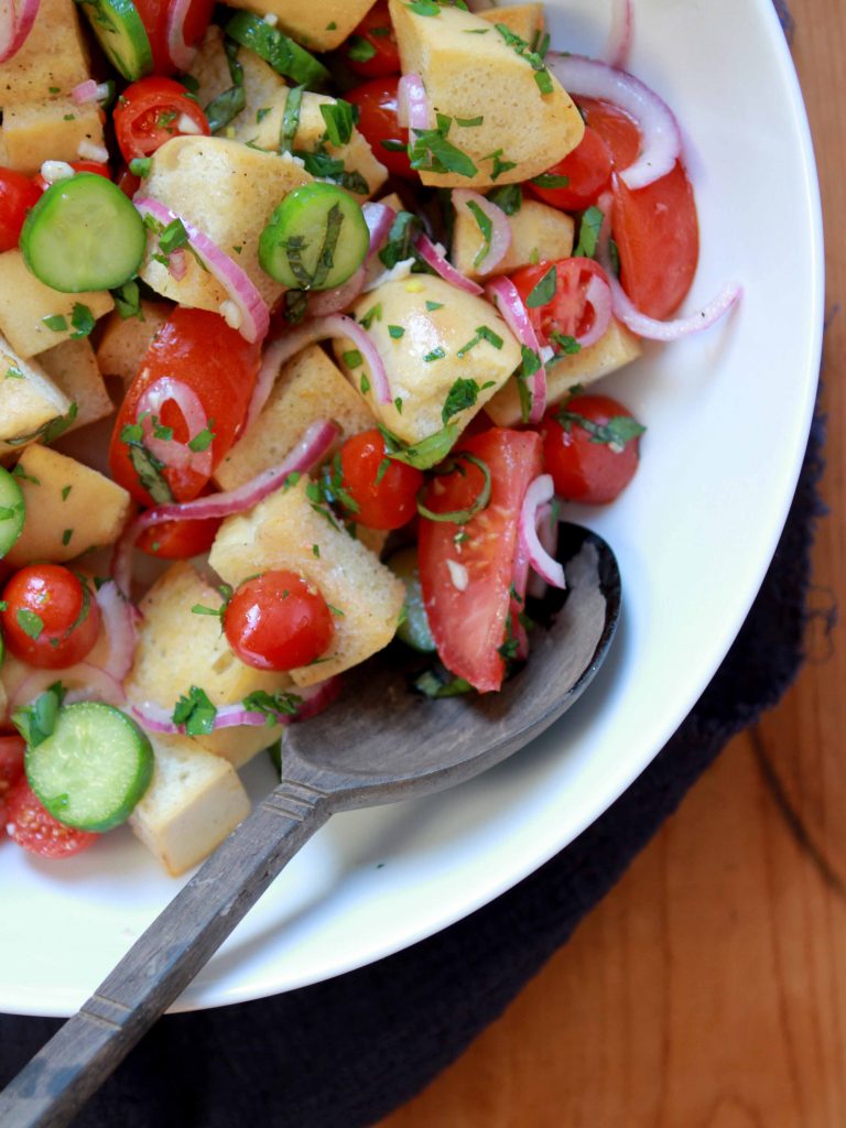 A top down view of a serving bowl of Keto Panzanella Italian Bread Salad with a spoon