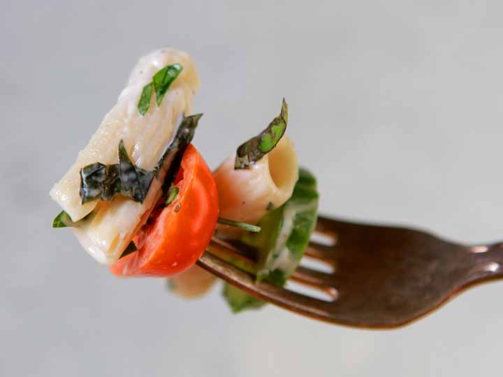 A fork holding a bite of healthy macaroni salad