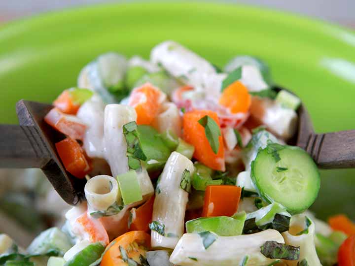 A wooden salad fork and spoon are picking up a serving of real low carb macaroni salad