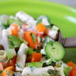 A wooden salad fork and spoon are picking up a serving of real low carb macaroni salad