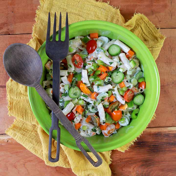 a top down view of a green bowl of low carb keto macaroni salad with a wooden