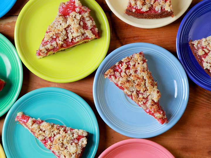 Green, blue and pink plates hold slices of low carb keto strawberry coffee cake