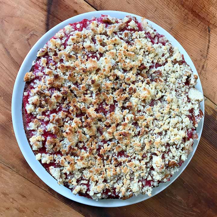 top down picture of a low carb keto strawberry crumb cake on a white plate against a wooden tabletop