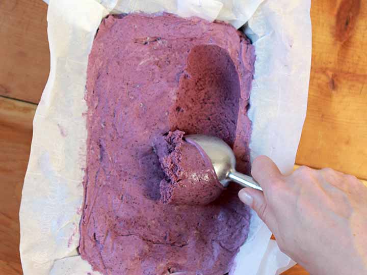 A hand scoops out a spoonful of a Blueberry Keto Frozen Treat