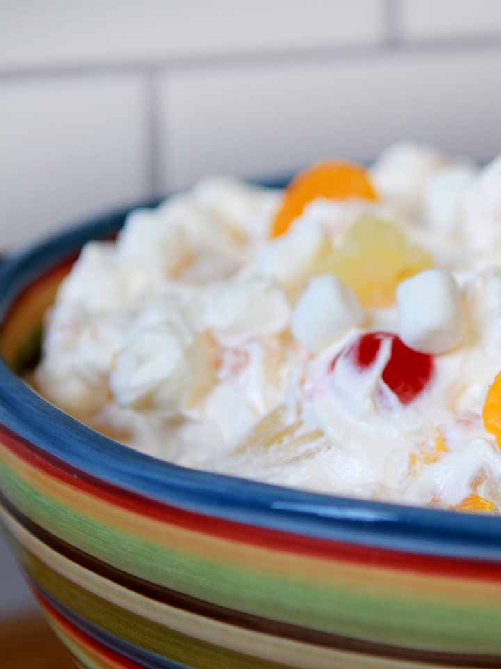 un colorido bol de Ambrosía fácil de hacer con Cool whip sobre un fondo de baldosas de metro