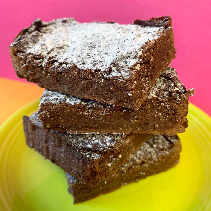 a stack of healthy avocado brownies on a green plate against a hot pink background