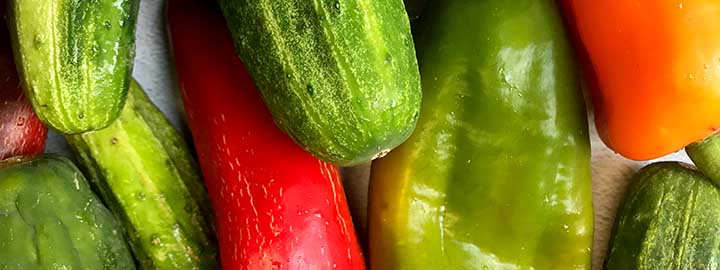 close up image of cucumbers and red, orange and green bell peppers