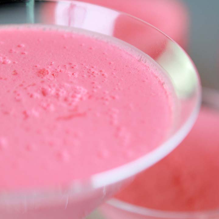 a close up image of a martini glass filled with bright pink Strawberry Fluff Salad