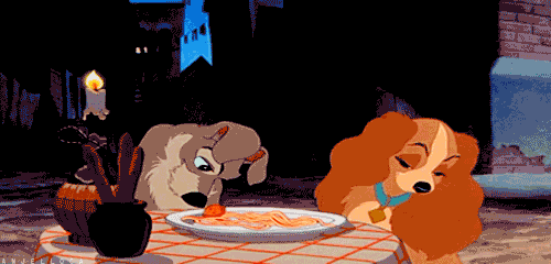 a gif of the Tramp pushing a meatball towards the Lady
