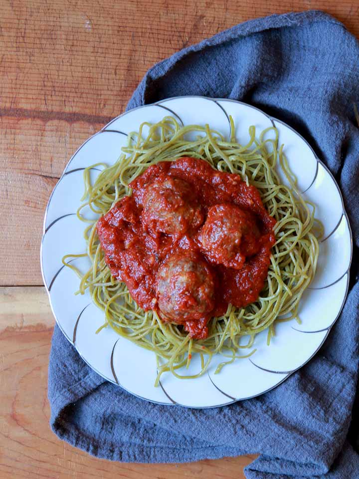 a plate of edamame spaghetti and meatballs on a fancy plate