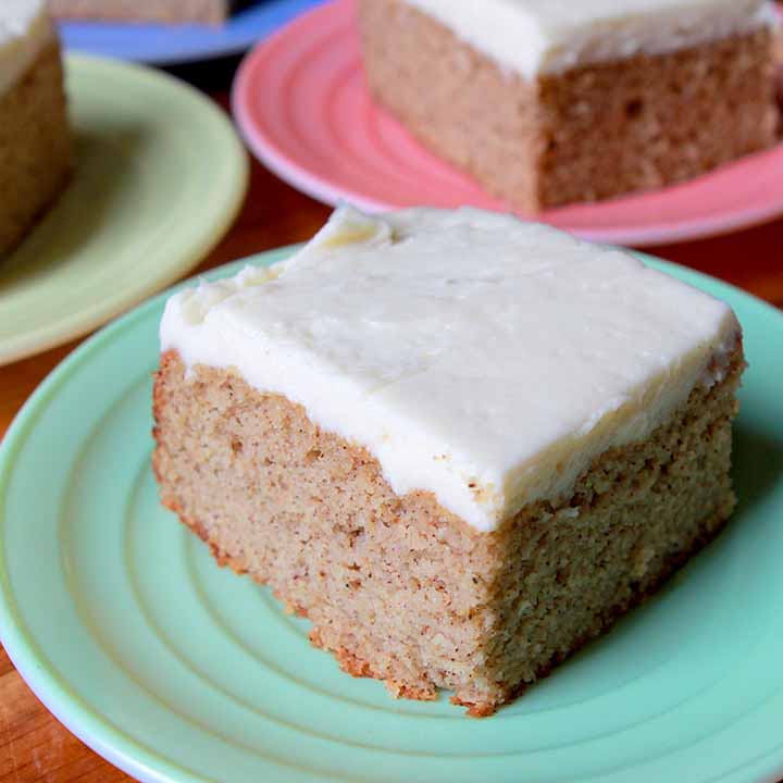 A piece of Keto spice cake on a green plate with more pieces of cake in the background